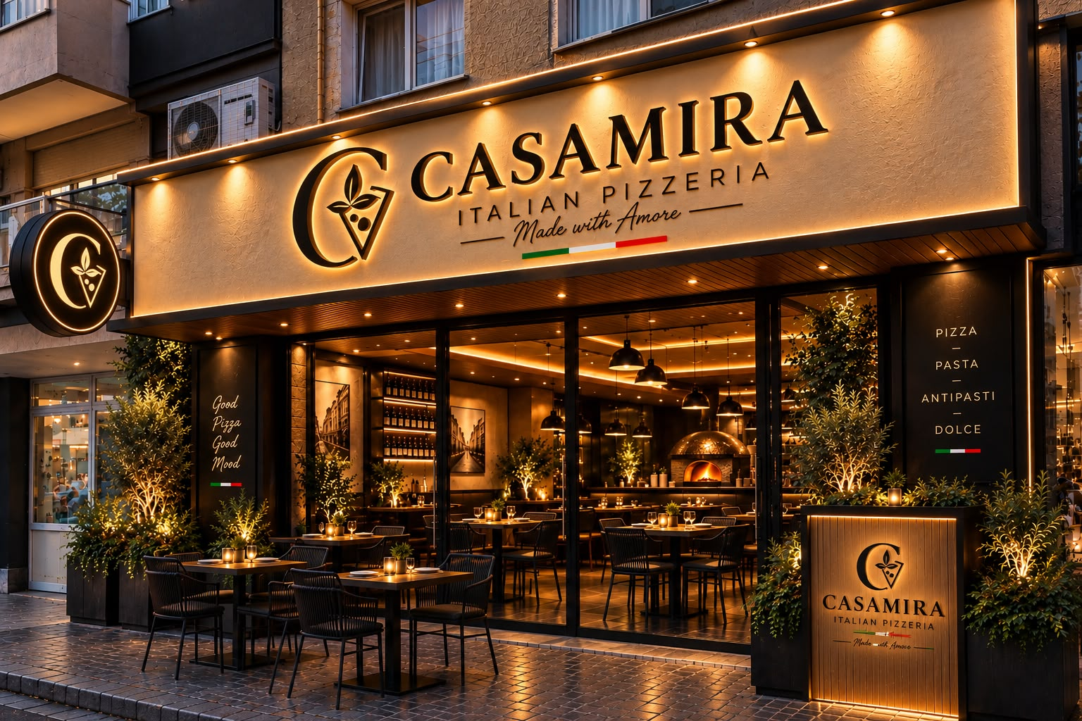 CASAMIRA'nın amber ışıklı tabelası, zeytin ağaçları ve davetkâr açık hava masaları